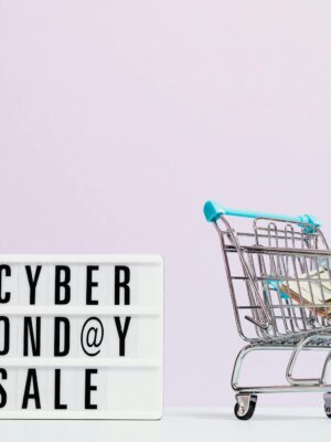 Shopping cart filled with cash beside a Cyber Monday sale sign, perfect for retail promotions.