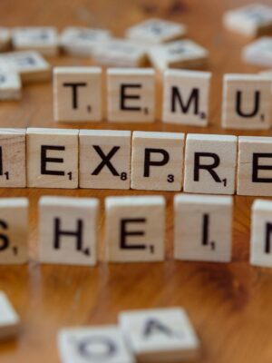 Wooden Scrabble tiles display popular e-commerce platforms on a wooden surface.